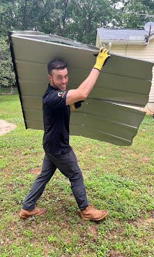 RID-ICK crew member carrying a large removed panel outdoors