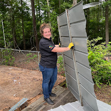 RID-ICK crew member carrying a large removed panel during a cleanout