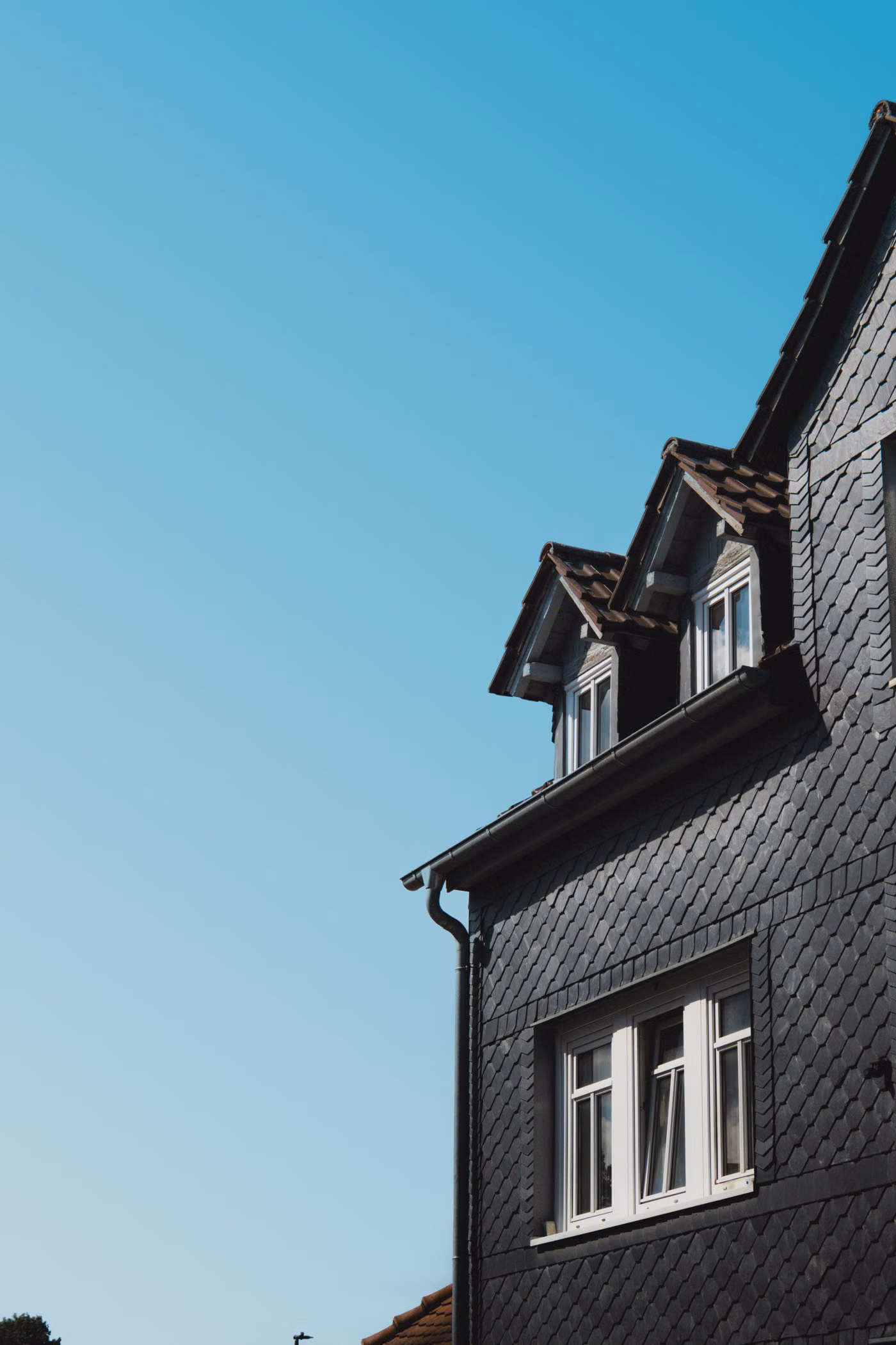Dark residential roofline with coordinated gutter and downspout